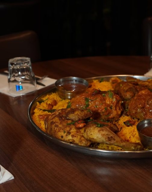 Mandi platter of slow-cooked chicken over spiced rice with sauces at Zaiqa London