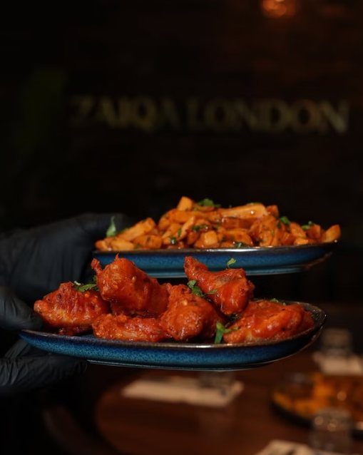 Chilli wings and masala chips carried out to a table at Zaiqa London