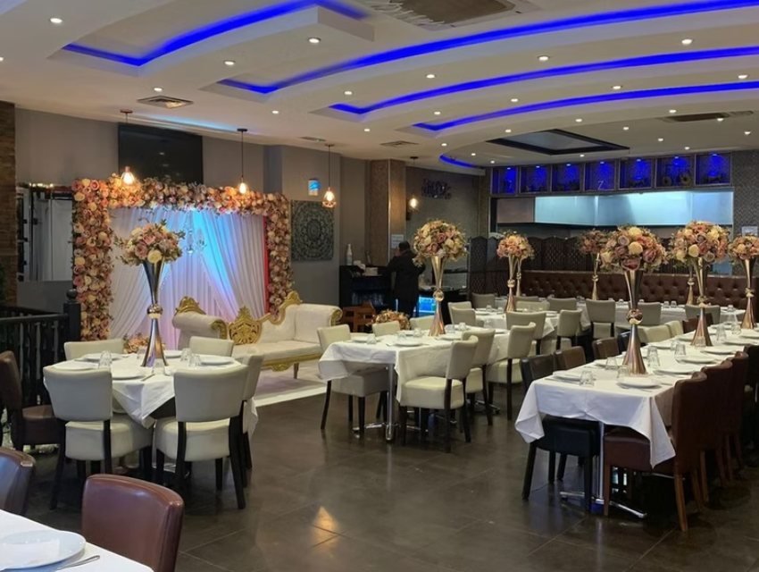 The main dining room at Zaiqa London laid out for a celebration, with a floral stage and long banquet tables