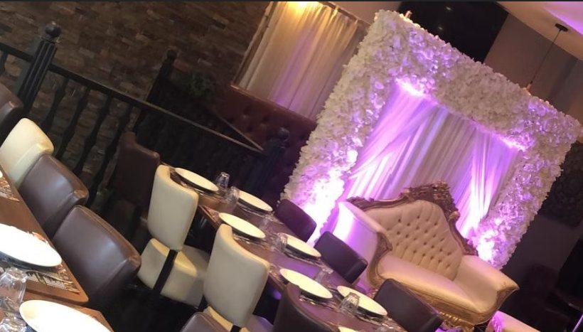 Floral backdrop and sweetheart seating set up for a wedding reception at Zaiqa London